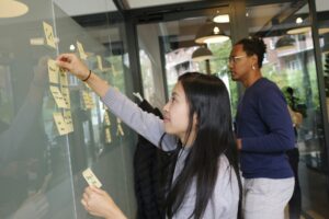 one woman writing and pasting post-it notes on a wall
